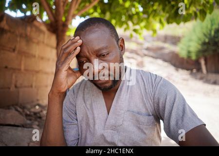 Worried black African villager thinking about his daily life problems Stock Photo