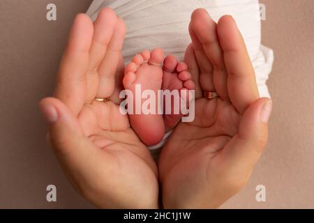 The palms of the father, the mother are holding the foot of the newborn Stock Photo