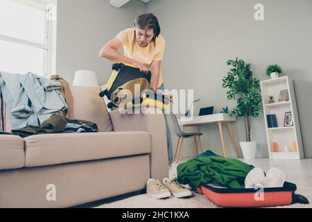 Photo of busy late hurry focused guy prepare travel suitcase pack things wear yellow t-shirt home indoors Stock Photo