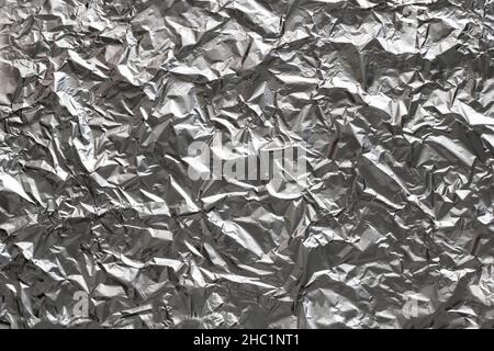 Textured background made of crumpled aluminum foil sheet. Top view. Stock Photo