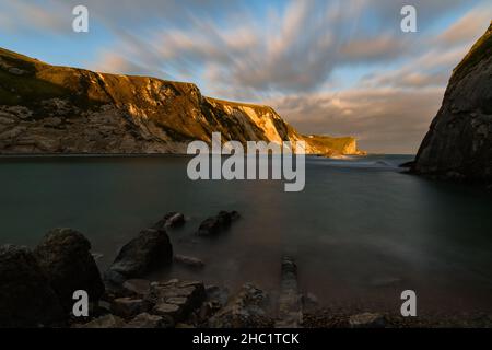 Man o' War Cove in Dorset, shortly before sunset, the sea & clouds blurred by the long exposure time used during capture. Stock Photo