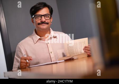 Man looking at camera while taking notes Stock Photo