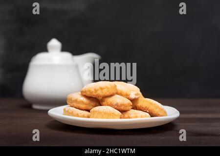 Shortbread cookies on white plate on wooden table side view. Baking for tea. Stock Photo