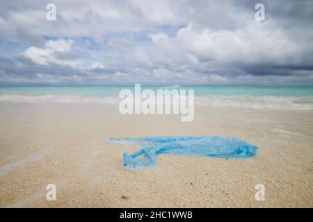Abandoned plastic bag on sand beach against sea. Themes ocean pollution and environmental Issues. Stock Photo