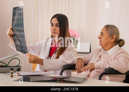 Lady doctor examining x-ray image of an old woman Stock Photo