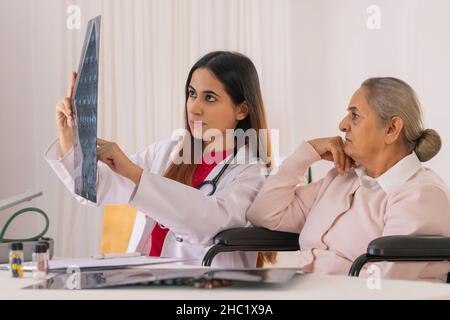 Lady doctor examining x-ray image of an old woman Stock Photo