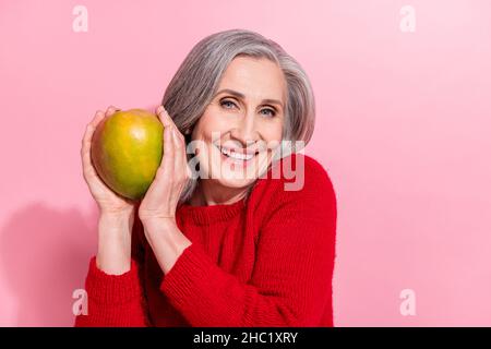 Portrait of attractive cheerful grey-haired woman holding mango organic menu isolated over pink pastel color background Stock Photo