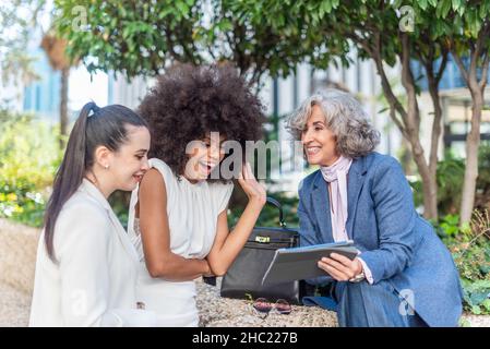 three female entrepreneurs watching something on the tablet Stock Photo