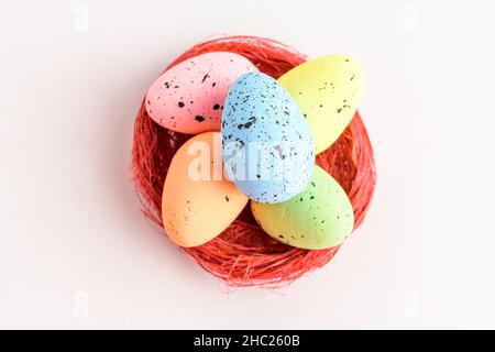 Mixed colored decorative red Easter eggs in a red rustic basket isolated on a white table Stock Photo