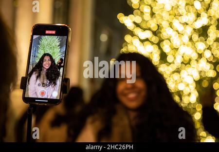 Chicago, USA. 19th Dec, 2021. A woman has her photo taken with a Christmas tree on Michigan Ave. in Chicago, the United States, Dec. 19, 2021. Credit: Joel Lerner/Xinhua/Alamy Live News Stock Photo