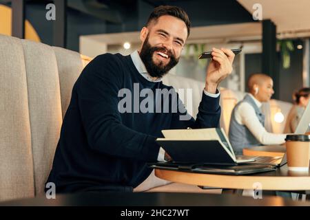 Smiling businessman making notes during a phone call. Happy young businessman making plans with his associates over the phone. Young entrepreneur work Stock Photo