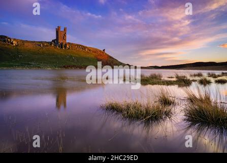 Dunstanburgh Castle reflections at sunset Embleton Bay Dunstanborough Northumberland coast England GB UK Europe Stock Photo