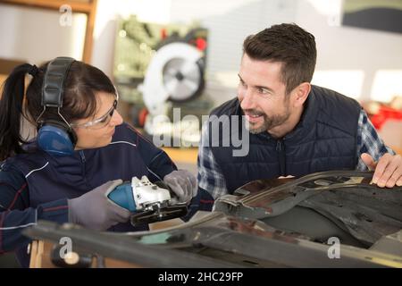 two mechanics - man and woman examining car engine Stock Photo