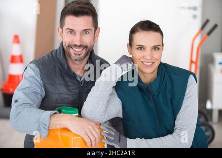 two workers leaning on plastic container in factory Stock Photo