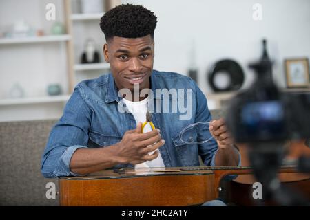 man filming a tutorial on how to restring a guitar Stock Photo