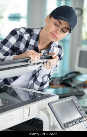 female technician using a screwdriver for fixing printer Stock Photo