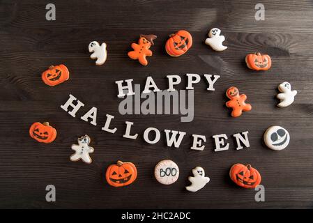 Funny delicious ginger cookies for Halloween on a dark wooden table. Top view. Inscription Happy Halloween , sweet background. Stock Photo