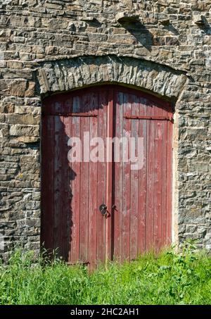 Red painted doors form the entrance to a traditional ston built barn in the Yorkshire Dales Stock Photo