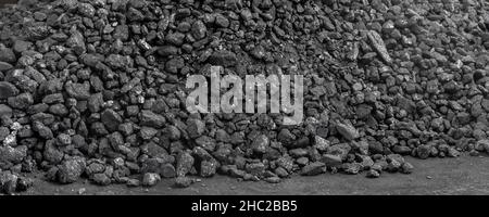 Big heap of dark black lump coal on floor bulk. Charcoal sorage at warehouse stock reserve. activated anthracite pile. Power and heat generation Stock Photo