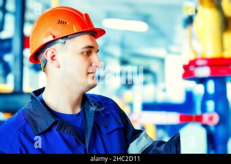 Portrait of engineer in helmet at work at gas processing plant. Worker checks equipment. Energy and gasification. Background. Stock Photo