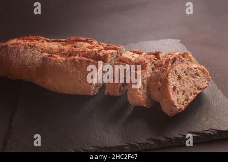 Fresh crispy French baguette on a black stone background. Wrapping crunchy french baguettes food photography with place for text. Stock Photo