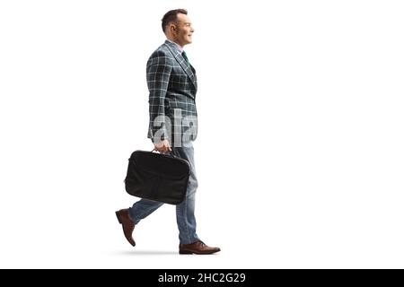 Full length profile shot of a man wearing a stylish suit and walking with a briefcase isolated on white background Stock Photo