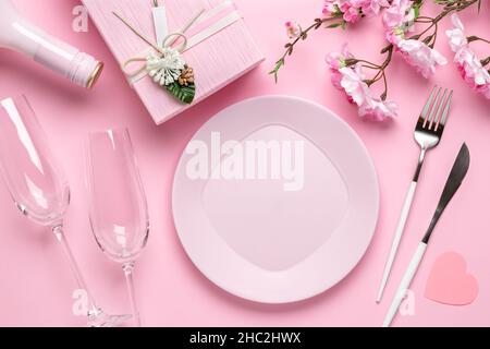 Romantic dinner, table setting on Valentine's Day. Dating concept, love. Spring flowers, empty plate, glasses, champagne, gift box, cutlery on a festi Stock Photo