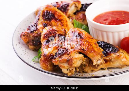 Baked chicken wings in the Asian style and tomatoes sauce on plate. Stock Photo