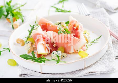 Appetizer with pear, blue cheese and prosciutto ham for holidays on a white plate. Stock Photo