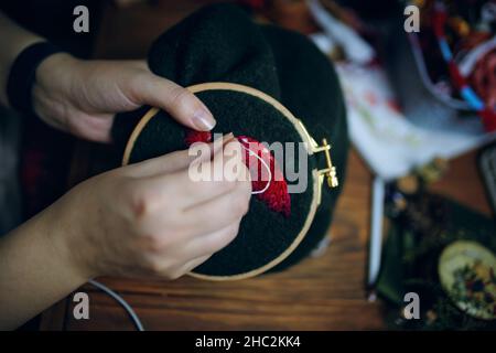 Women's hands embroiders fly agaric hat on frame. Stock Photo