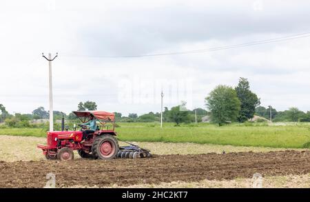 Jawai, Rajasthan, India - September 2021: Indian farmer harvesting the new crop with tractor in the agricultural field. Stock Photo