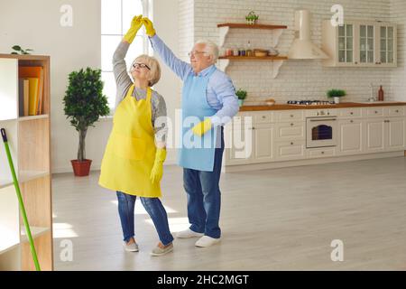 Happy senior couple having fun and dancing while tidying up their new apartment Stock Photo