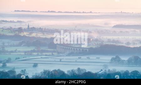 The view across Arthington Pastures form Otley Chevin on a freezing, hazy December morning. Arthington Viaduct is visible within the layers. Stock Photo