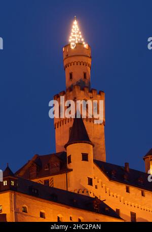 Braubach, Germany. 23rd Dec, 2021. A Christmas tree lights up on the tower of Marksburg Castle on the Middle Rhine near Braubach. Marksburg Castle, which stands on a 160-metre-high slate cone high above the Rhine, is the only medieval hilltop castle on the Rhine that has never been destroyed. Credit: Thomas Frey/dpa/Alamy Live News Stock Photo