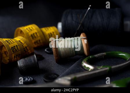 Retro tools for cutting and sewing. Needle with thread, thimble, centimeter and scissors. Tailor and seamstress Stock Photo