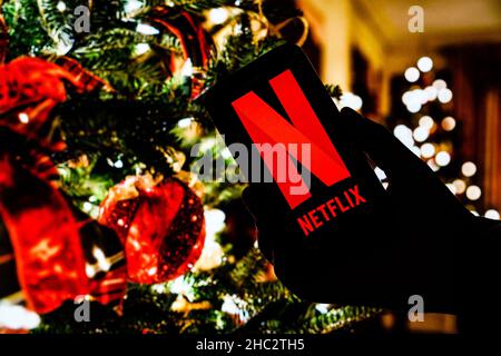 Poland. 21st Dec, 2021. In this photo illustration the Netflix logo seen displayed on a smartphone and Christmas decorations in the background. (Photo by Filip Radwanski/SOPA Images/Sipa USA) Credit: Sipa USA/Alamy Live News Stock Photo