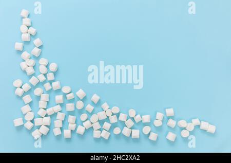 Marshmallows on pastel blue background, copy space. White fluffy mini dessert, kids birthday party invitation template. Stock Photo