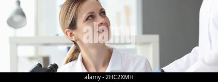Scientists in laboratory use microscope and record results closeup Stock Photo