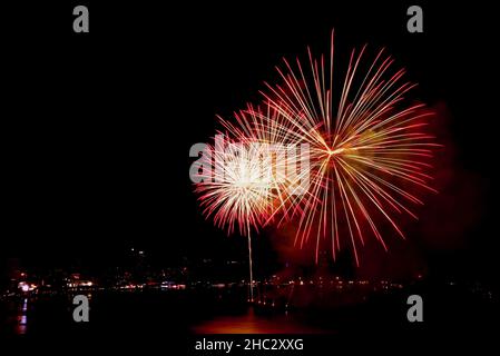 Spectacular red and gold fireworks exploding in to the night sky over the bay Stock Photo