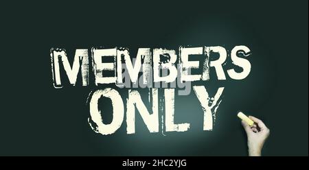 Members Only in pale yellow on blackboard and hand with chalk. VIP special services Business concept. Stock Photo