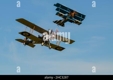 Great War dogfight re-creation at an airshow. RFC/RAF Royal Aircraft Factory R.E.8 A3930 and Luftstreitkräfte Fokker Dr.I Dreidecker triplane fighter Stock Photo