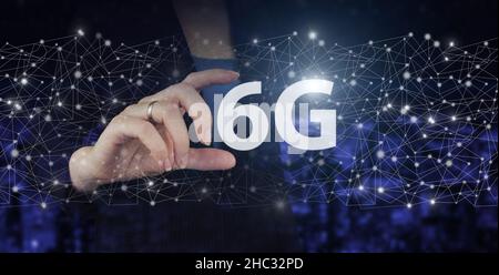 The concept of 6G network, high-speed mobile Internet, new generation networks. Hand hold digital hologram 6G sign on city dark blurred background. Gl Stock Photo