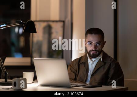 Overwork before project deadline: casual man programmer or web developer staying late in office Stock Photo