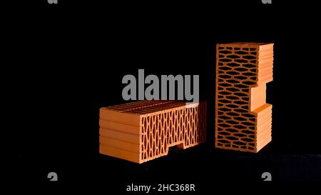 Wall construction materials, small pile of ceramic blocks isolated on black background. Red new perforated bricks. Stock Photo