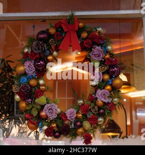 London, Greater London, England, December 15 2021: Festive bouquet with a ribbon hanging in a window. Stock Photo