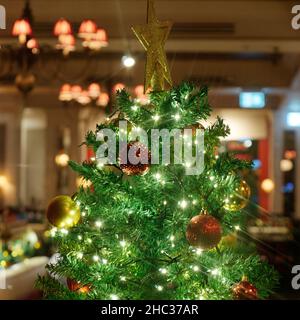 London, Greater London, England, December 15 2021: Top of a Christmas Tree with decorations and a star in a restaurant. Stock Photo