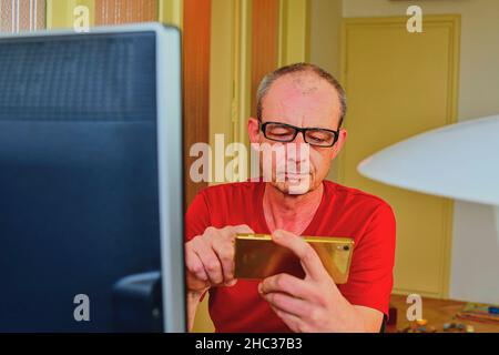 Middle aged man with glasses sitting at desk. Mature man using mobile phone. Senior concept. Man at home office Stock Photo