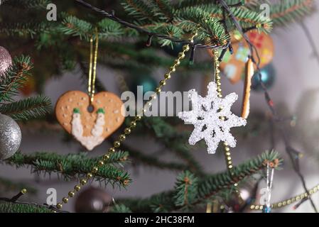Christmas decorations hung on a natural spruce tree. Christmas balls, hand-decorated gingerbreads and chains on the Christmas tree. Stock Photo