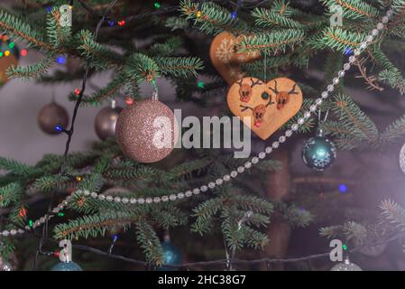 Christmas decorations hung on a natural spruce tree. Christmas balls, hand-decorated gingerbreads and chains on the Christmas tree. Stock Photo