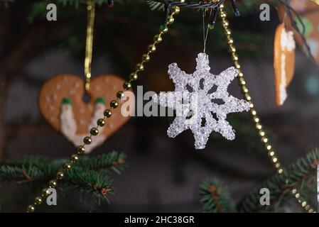 Christmas decorations hung on a natural spruce tree. Christmas balls, hand-decorated gingerbreads and chains on the Christmas tree. Stock Photo